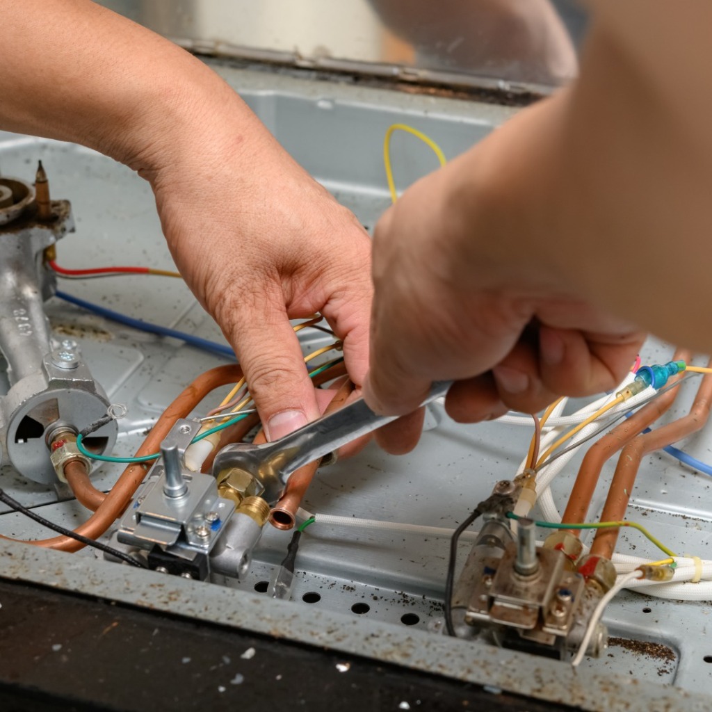 Technician servicing gas range manifold and valve assembly
